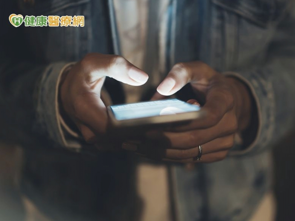 在夜晚玩手機的照片