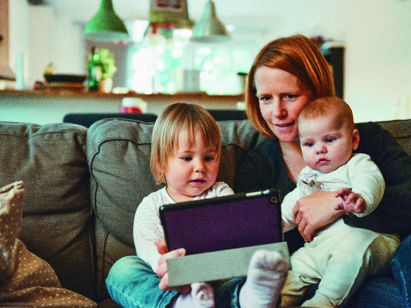 一位母親陪伴小孩玩手機的照片